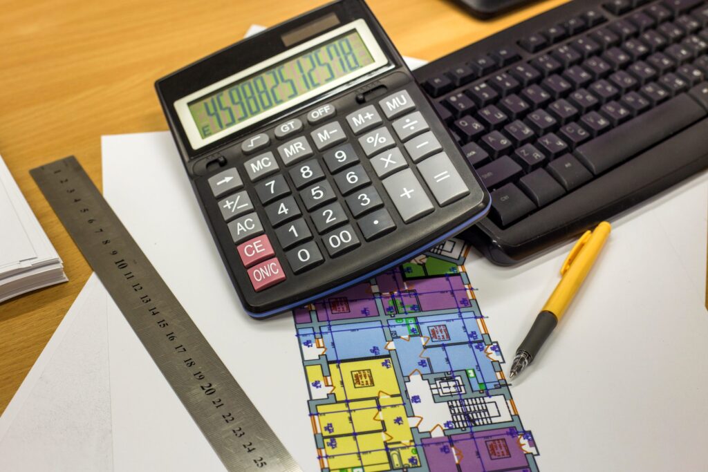 calculadora em cima de papéis com fórmulas matemáticas escritas.