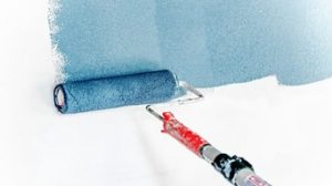 Um rolo de pintura pintando uma parede branca de azul.