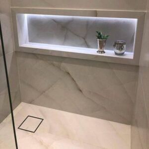 Banheiro em mármore cinza e marrom com um nicho de porcelanato.