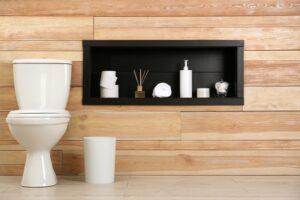 Banheiro com parede em porcelanato marrom e abertura em madeira para colocar coisas.
